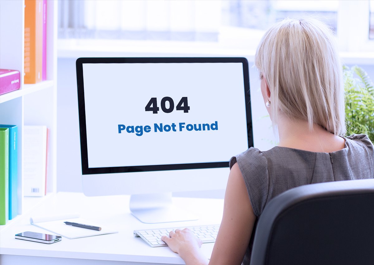 woman sitting at a desk looking at a computer screen with a 404 error message